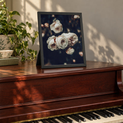Cold Desdemona, 8×10 inch print shown in a styled room mockup. Cluster of ivory roses against a dark, softly blurred garden. Frame shown for styling; print sold unframed.