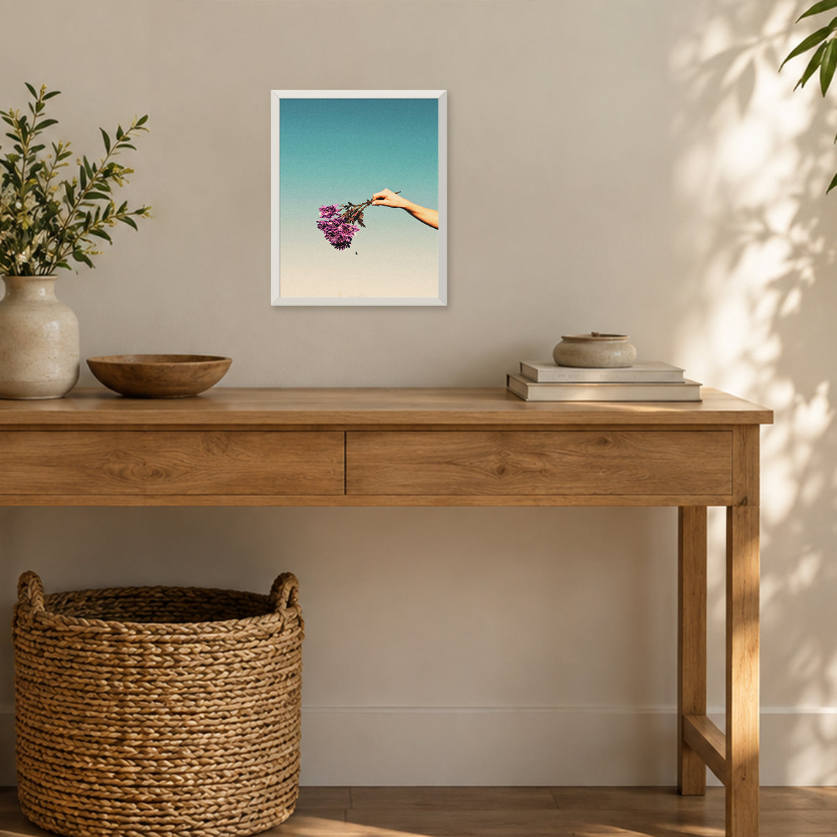 Cries of the Chrysanthemum, 8×10 inch print shown in a styled room mockup. Outstretched hand holding a small purple bouquet against a pale blue sky. Frame shown for styling; print sold unframed.