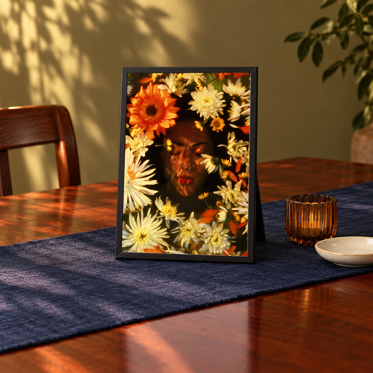Ophelia's Dream, 5×7 inch print shown in a styled room mockup. Face framed by orange, cream, and yellow flowers in a warm-toned portrait. Frame shown for styling; print sold unframed.