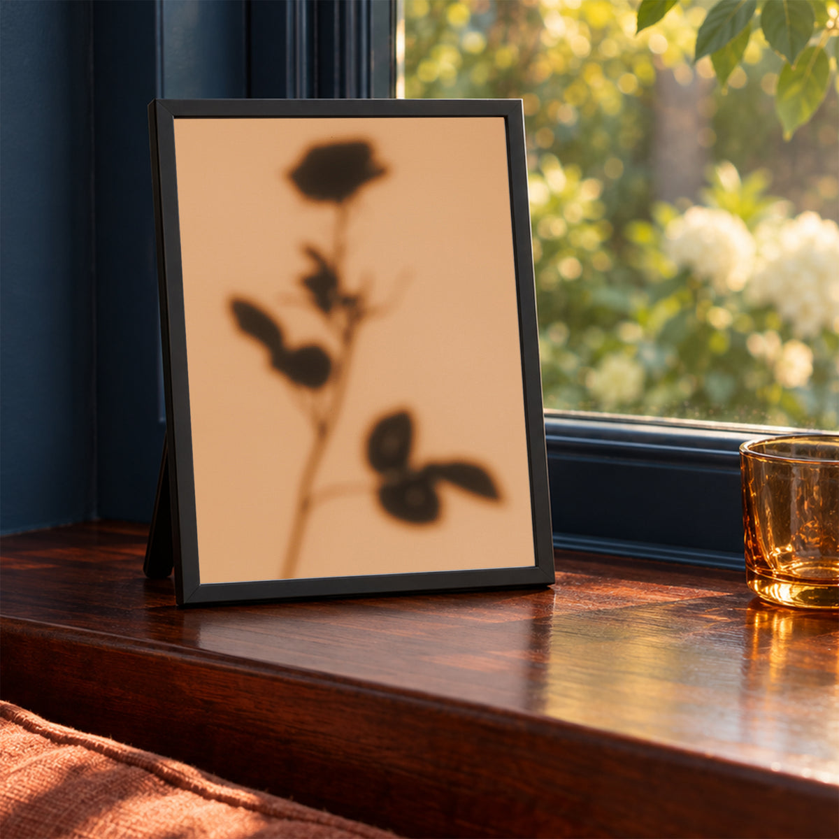 Shadow of Duet, 5×7 inch print shown in a styled room mockup. Soft shadow of a rose stem cast across a warm peach background. Frame shown for styling; print sold unframed.
